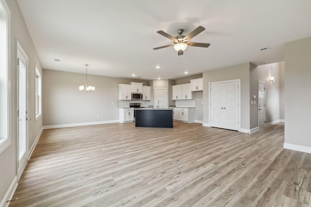 unfurnished living room featuring recessed lighting, light wood-style floors, baseboards, and ceiling fan with notable chandelier
