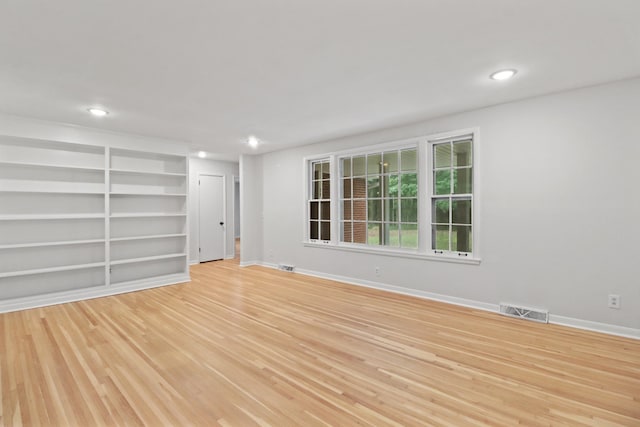 empty room with recessed lighting, visible vents, light wood-type flooring, baseboards, and built in features