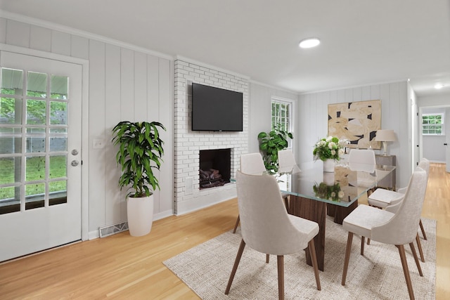 dining space featuring crown molding, wood finished floors, visible vents, and a fireplace