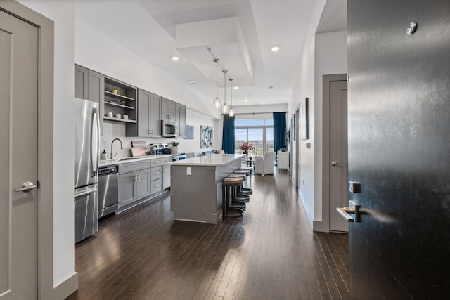 kitchen with gray cabinets, appliances with stainless steel finishes, open shelves, and a kitchen island