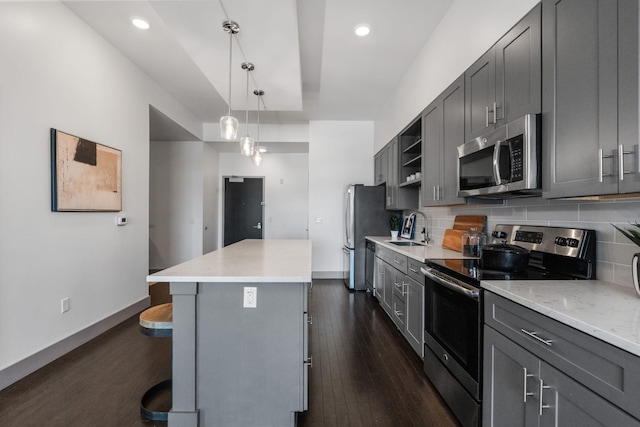 kitchen with stainless steel appliances, gray cabinetry, a sink, and dark wood finished floors