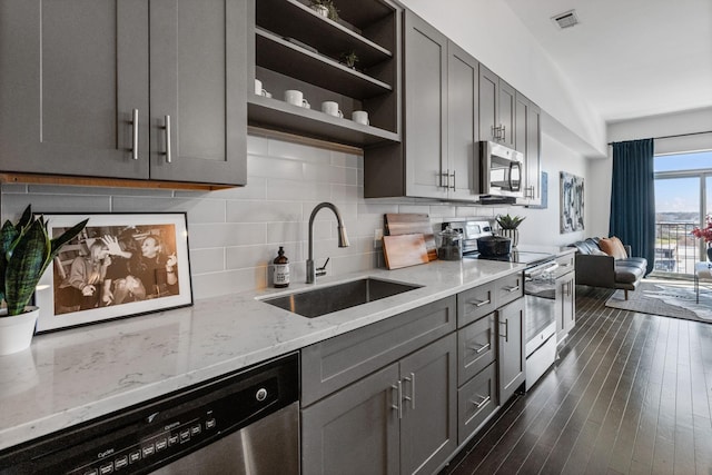 kitchen with light stone counters, a sink, gray cabinets, appliances with stainless steel finishes, and visible vents