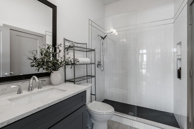 bathroom featuring toilet, vanity, and tiled shower