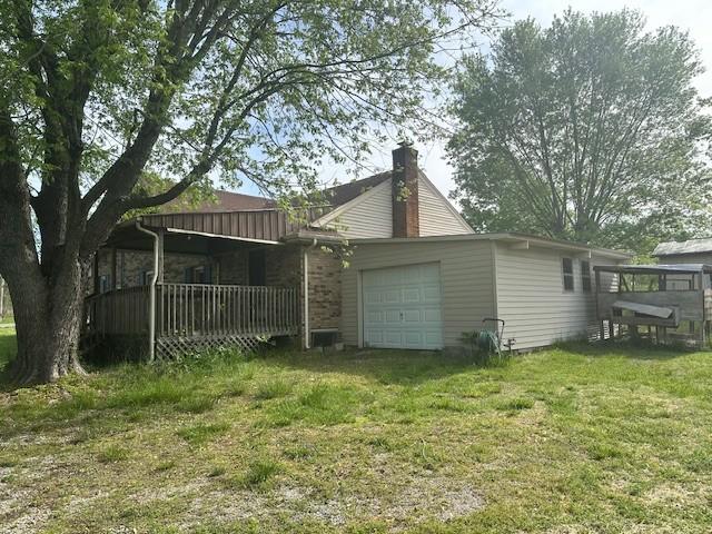 view of side of home featuring a lawn, a chimney, and a garage