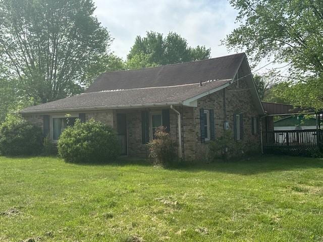 view of front of property featuring brick siding, a front yard, and a deck
