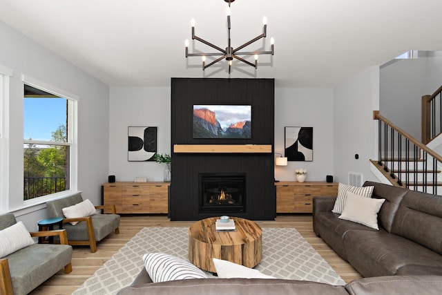 living room featuring stairway, visible vents, light wood-style flooring, and a chandelier