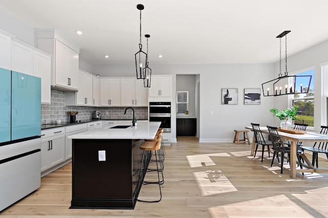 kitchen featuring freestanding refrigerator, baseboards, white cabinetry, tasteful backsplash, and a sink