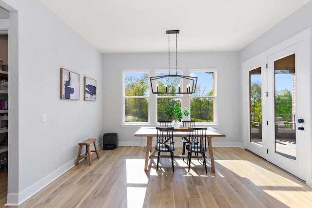 dining room with baseboards, an inviting chandelier, and light wood-style flooring