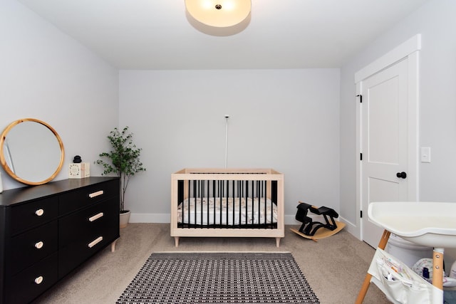 bedroom with carpet floors, baseboards, and a crib