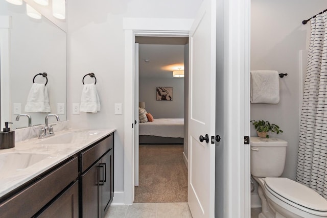 bathroom with tile patterned flooring, double vanity, toilet, ensuite bathroom, and a sink