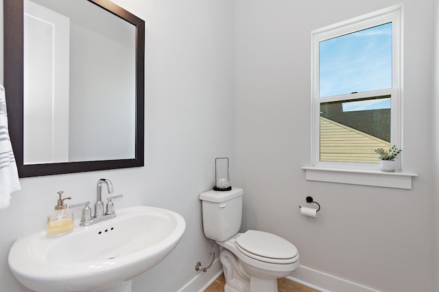 bathroom with baseboards, a sink, wood finished floors, and toilet