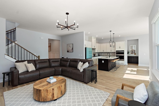 living area featuring light wood-type flooring, recessed lighting, a notable chandelier, and stairway