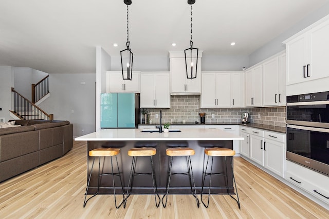 kitchen featuring backsplash, a kitchen bar, a sink, freestanding refrigerator, and double oven