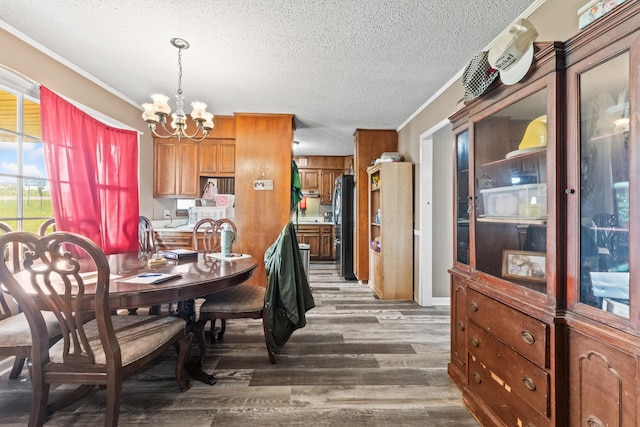 dining room with ornamental molding, a notable chandelier, a textured ceiling, and wood finished floors