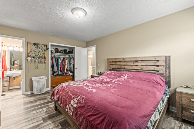 bedroom with wood finished floors, a textured ceiling, a closet, and ensuite bathroom