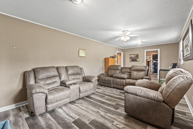 living room featuring crown molding, a ceiling fan, wood finished floors, and a textured ceiling