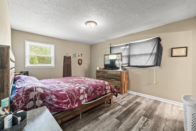 bedroom featuring a textured ceiling, wood finished floors, and baseboards