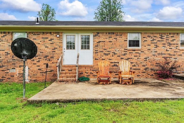 rear view of house with a lawn, a patio area, entry steps, and brick siding