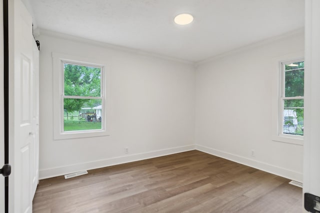 unfurnished room featuring wood finished floors, a healthy amount of sunlight, and crown molding