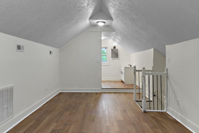 bonus room featuring a textured ceiling, wood finished floors, visible vents, and baseboards