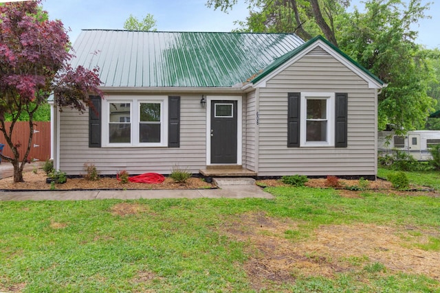 ranch-style house featuring fence, a front yard, and metal roof