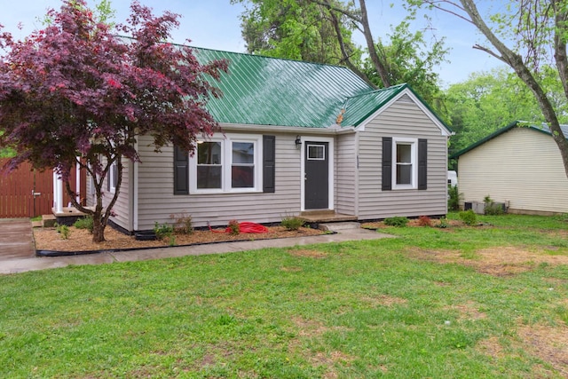 ranch-style home with a front yard and metal roof
