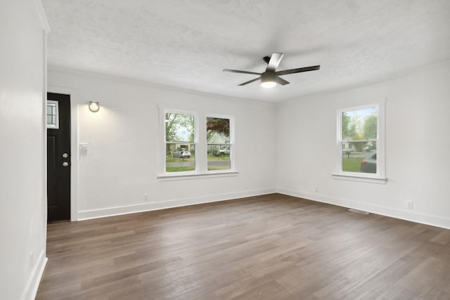 empty room with dark wood finished floors, ceiling fan, and a healthy amount of sunlight