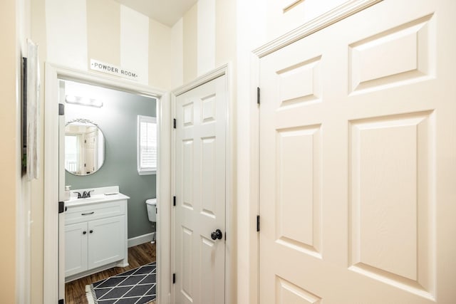 half bathroom featuring wood finished floors, vanity, and toilet