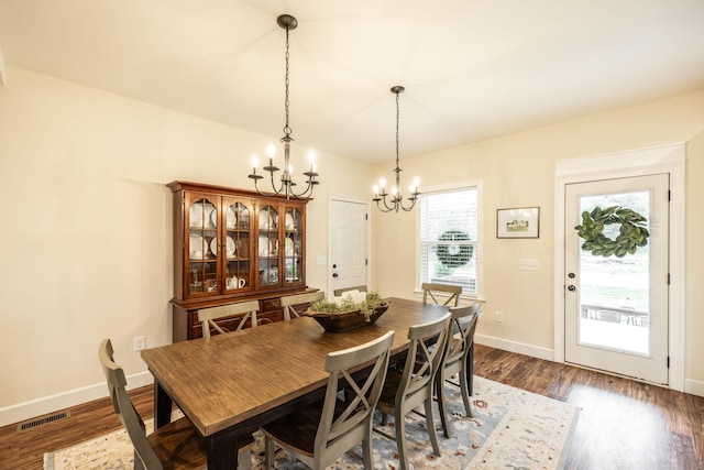 dining room featuring dark wood finished floors, visible vents, baseboards, and an inviting chandelier