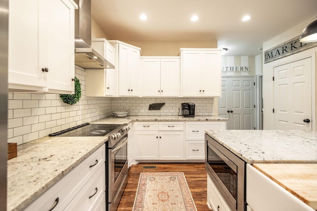 kitchen featuring wall chimney exhaust hood, stainless steel appliances, white cabinets, and dark wood-style flooring