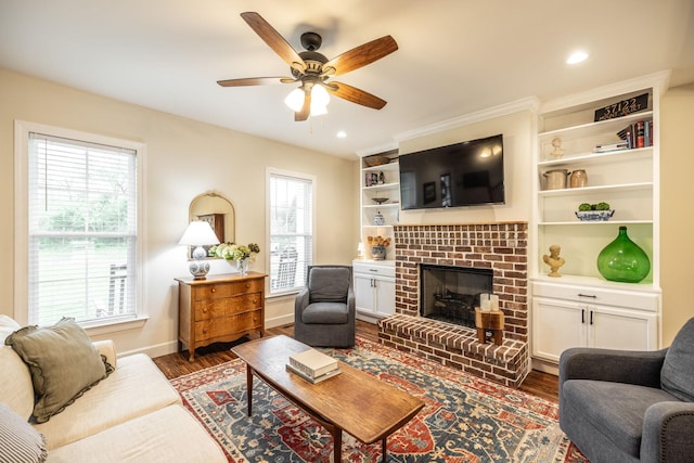 living room with ceiling fan, a brick fireplace, dark wood-type flooring, and plenty of natural light