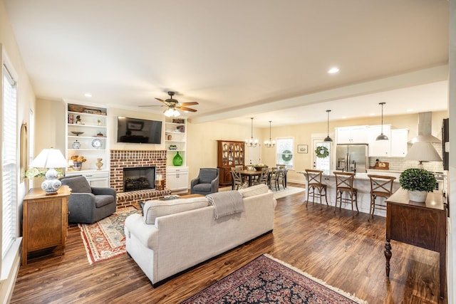 living area featuring ceiling fan, a brick fireplace, dark wood-style floors, and recessed lighting