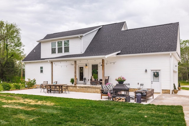 rear view of property with a fire pit, a patio, a shingled roof, and a lawn