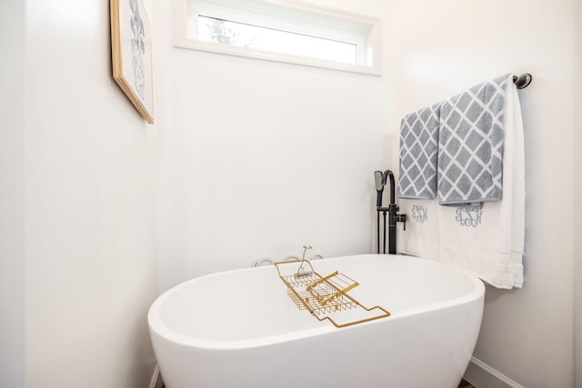 full bath featuring a freestanding bath and baseboards