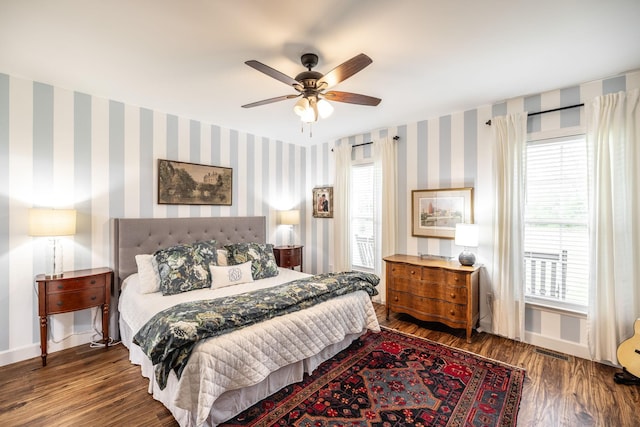 bedroom featuring visible vents, baseboards, wood finished floors, and wallpapered walls