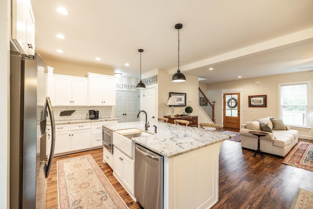 kitchen featuring a sink, decorative backsplash, open floor plan, stainless steel appliances, and dark wood-type flooring