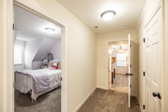 hallway featuring carpet floors, visible vents, and baseboards