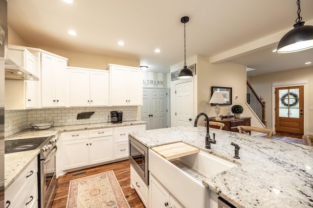 kitchen with wall chimney range hood, tasteful backsplash, stainless steel appliances, and white cabinetry
