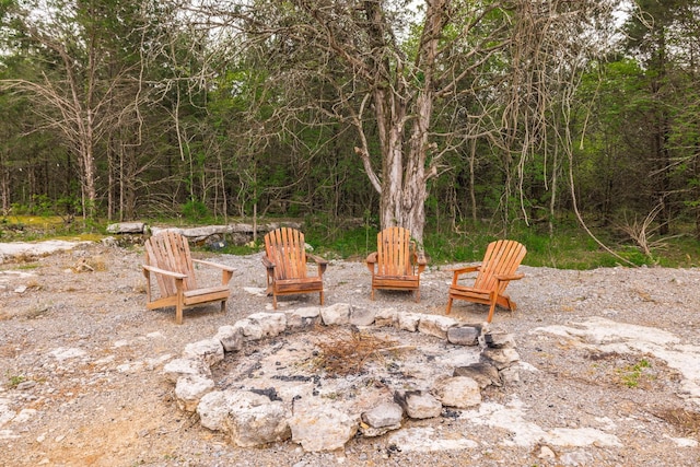 view of patio featuring a fire pit and a wooded view