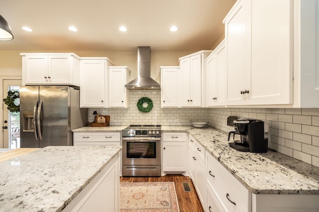 kitchen featuring wall chimney exhaust hood, white cabinets, dark wood-type flooring, and appliances with stainless steel finishes