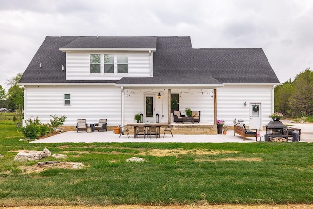 back of property with a yard, a patio, and a shingled roof