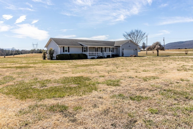 single story home featuring an attached garage, a rural view, a front lawn, and covered porch