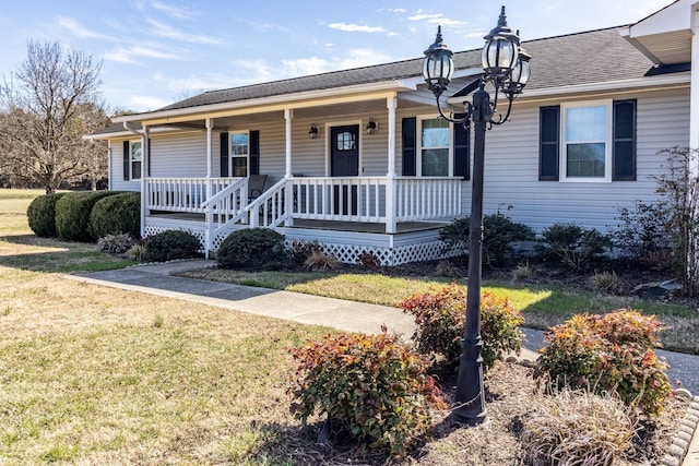 view of front facade with a shingled roof, a front lawn, and covered porch