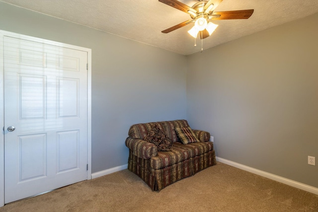 sitting room with light carpet, baseboards, a textured ceiling, and ceiling fan