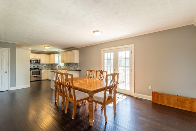 dining space featuring a textured ceiling, dark wood-style flooring, visible vents, baseboards, and ornamental molding