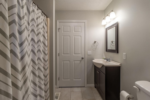 bathroom featuring tile patterned floors, visible vents, toilet, vanity, and a textured ceiling