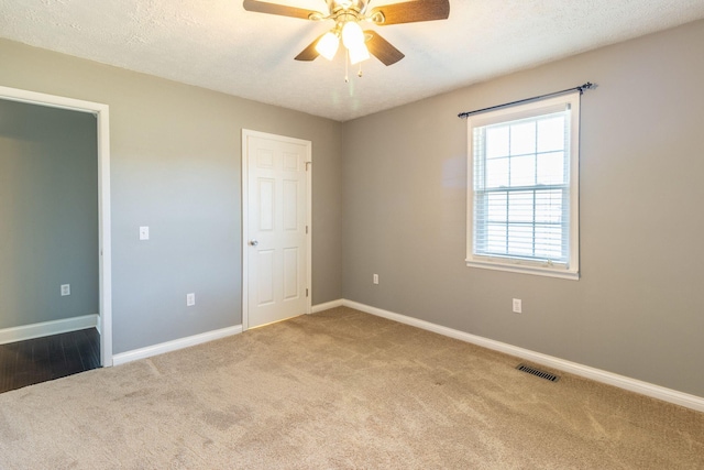 carpeted spare room with baseboards, a ceiling fan, and visible vents