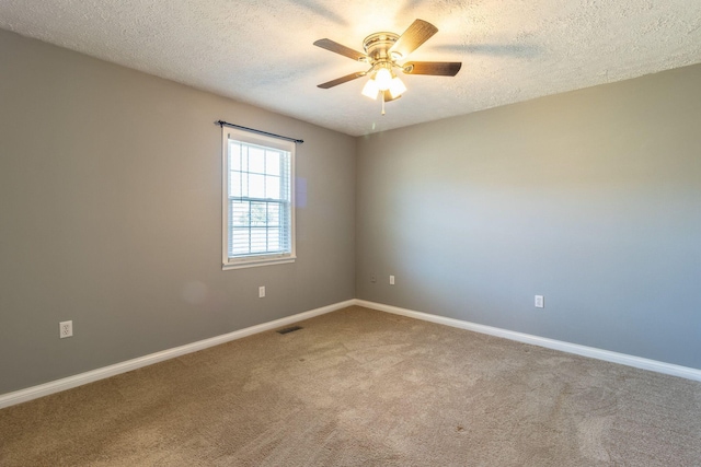 carpeted empty room featuring ceiling fan, baseboards, a textured ceiling, and visible vents