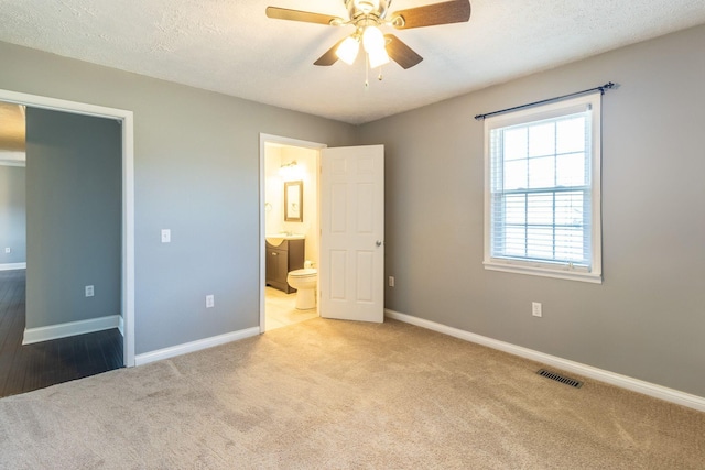 unfurnished bedroom with carpet, visible vents, baseboards, and ensuite bathroom