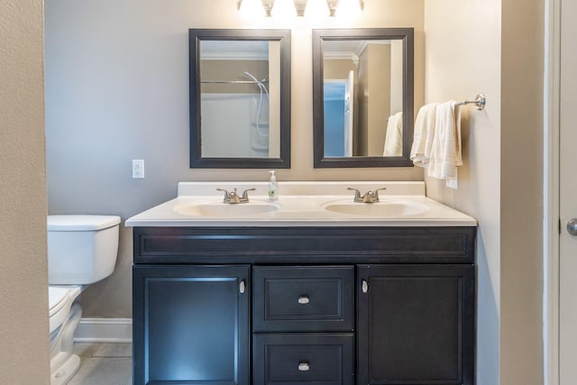 full bathroom featuring double vanity, toilet, baseboards, and a sink